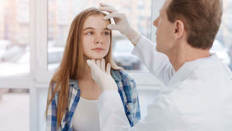 A doctor checking up the acne of young lady