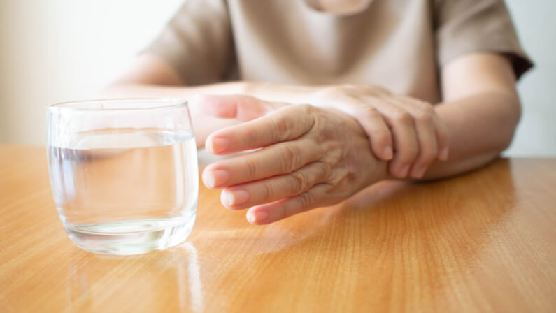 Woman with Parkinsons disease can't grasp the glass of water