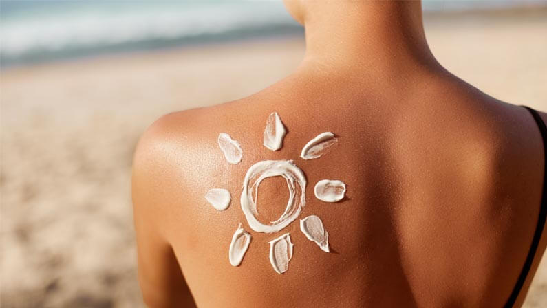 Woman on a beach wearing sunscreen on her back drawn as sun
